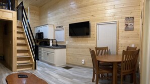 Cocina compacta con zona de comedor, pisos de madera, televisor montado en la pared y un cartel que indica una zona de pesca.