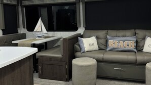 A cozy living area with a sofa, ottoman, and a small table. A sign above reads "Beach". - Vacation Paradise478 (Key Largo)