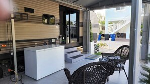 A covered outdoor area with a white kitchen counter, wicker chairs, and a small table. - Vacation Paradise478 (Key Largo)