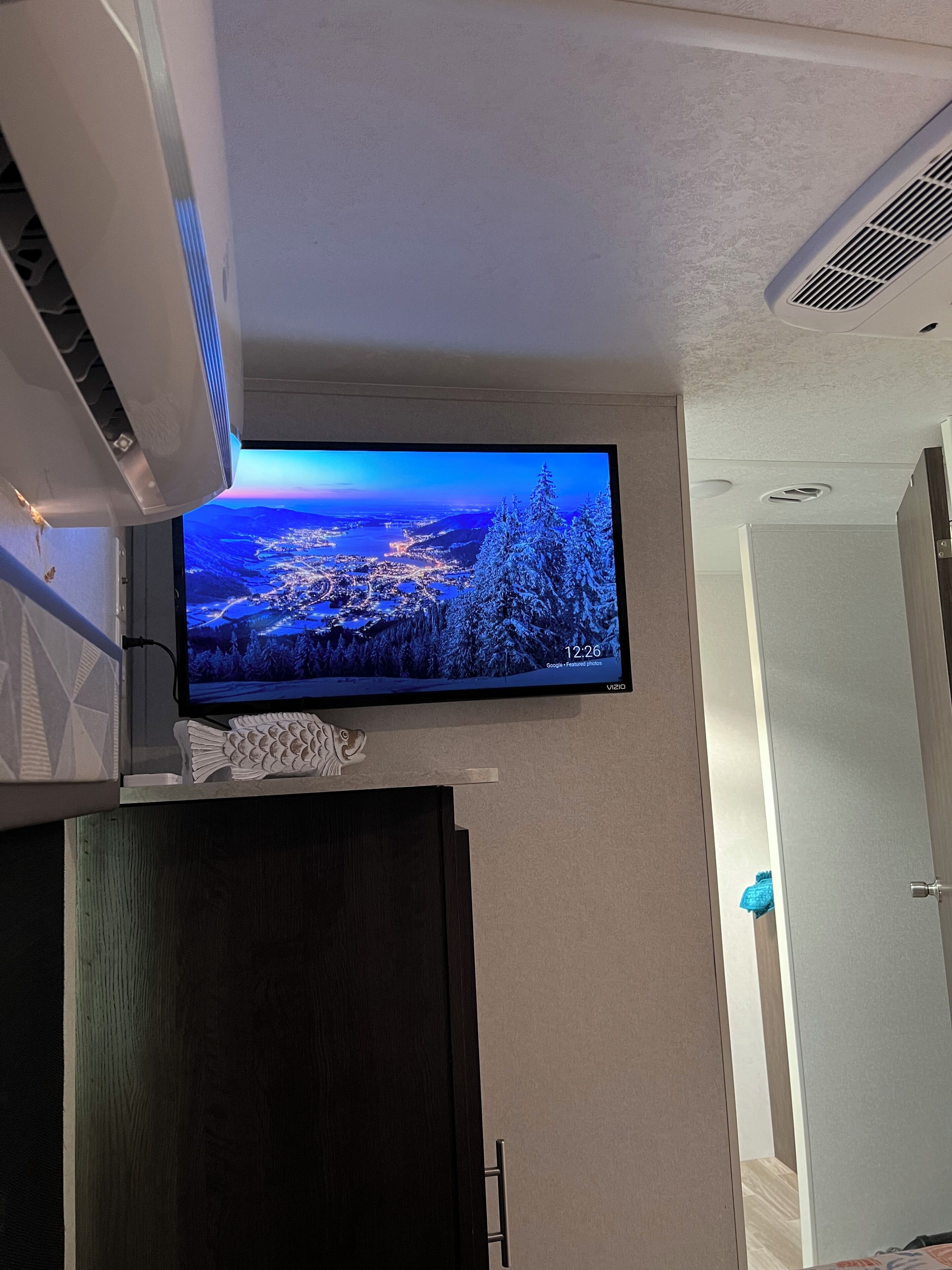 A flat-screen TV mounted on a wall displaying a scenic landscape.