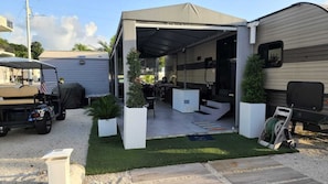 A covered outdoor area with a patio, seating, and a golf cart.