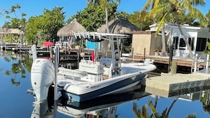 A boat docked at a marina with a thatched-roof structure nearby. - Vacation Paradise478 (Key Largo)