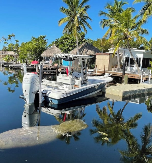 A boat docked at a marina with a thatched-roof structure nearby.