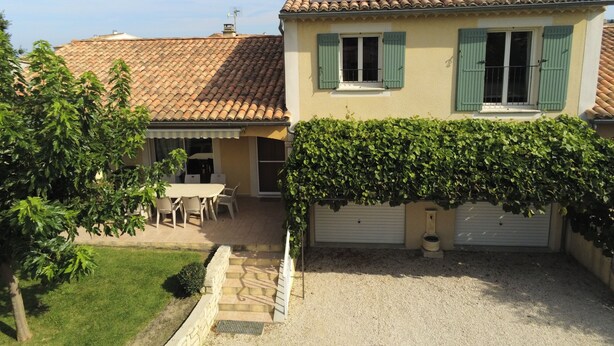 A house with a tiled roof, a covered patio with outdoor furniture, and a garage with a white door. - 8-person villa with private pool at the foot of Mont Ventoux (Malaucène)