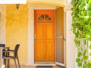 Une porte en bois avec un panneau de verre, un portail en métal et une chaise à l’extérieur.
