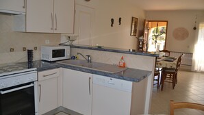 A kitchen with a microwave, oven, and dishwasher. There is a dining area with a table and chairs. - 8-person villa with private pool at the foot of Mont Ventoux (Malaucène)