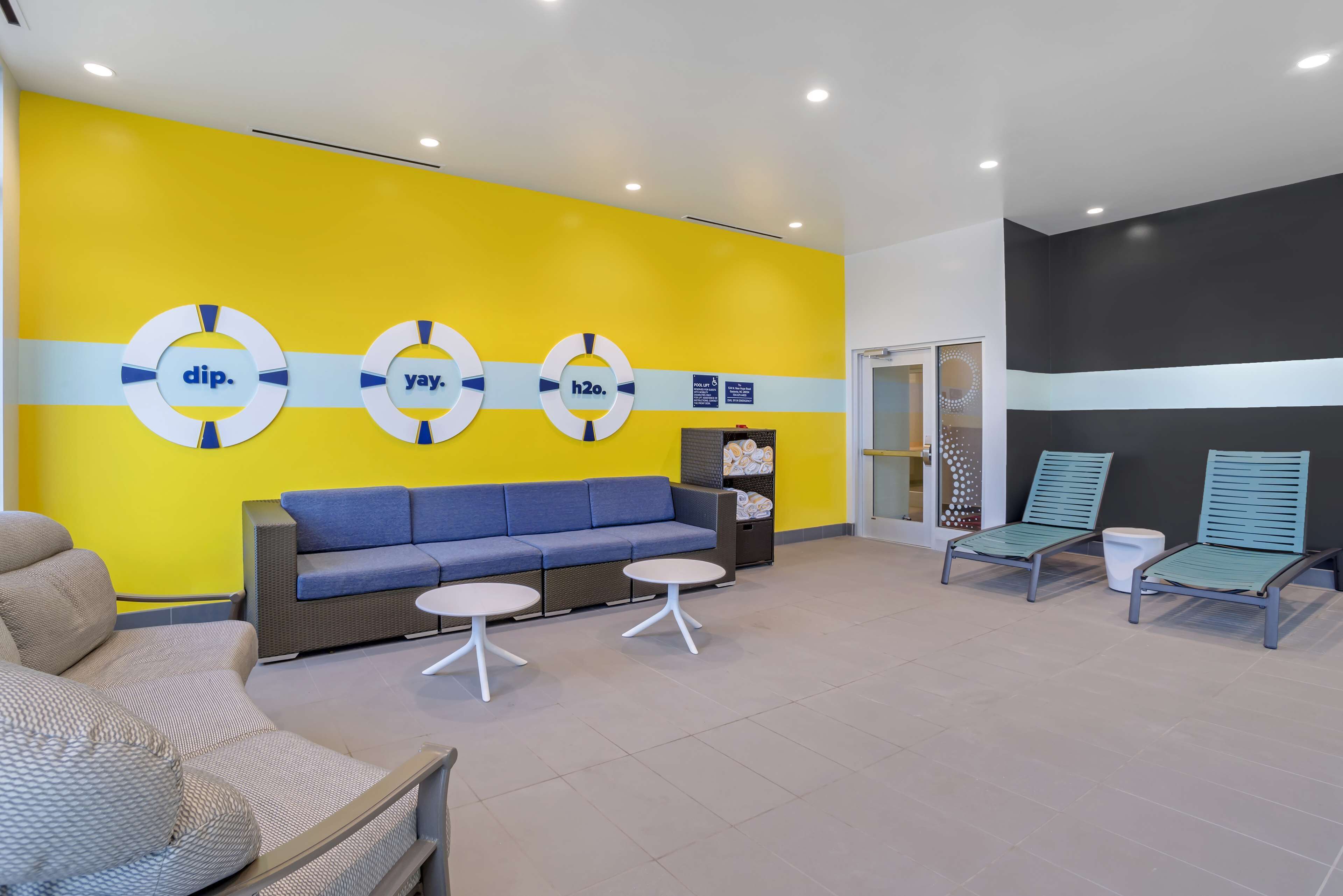 A modern waiting area with a yellow wall, blue sofa, and lounge chairs.