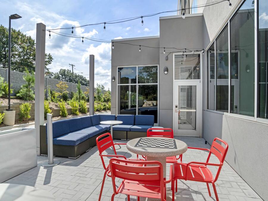 Un patio al aire libre con un sofá azul, sillas rojas y una mesa.