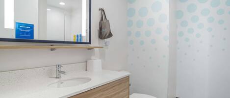 A modern bathroom with a wooden vanity, a sink, a toilet, and a mirror.