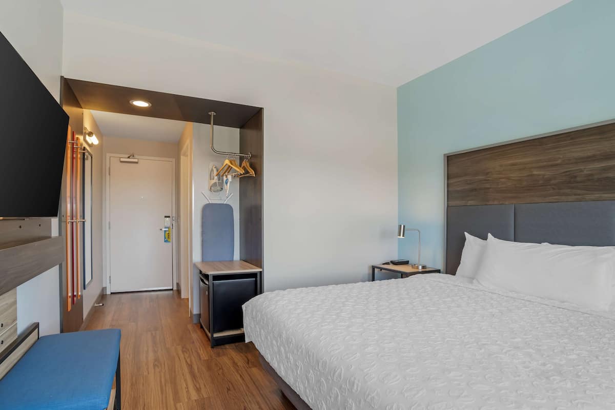 Ein modernes Hotelzimmer mit einem großen Bett, einem Schreibtisch, einem Sessel und einem Fernseher.