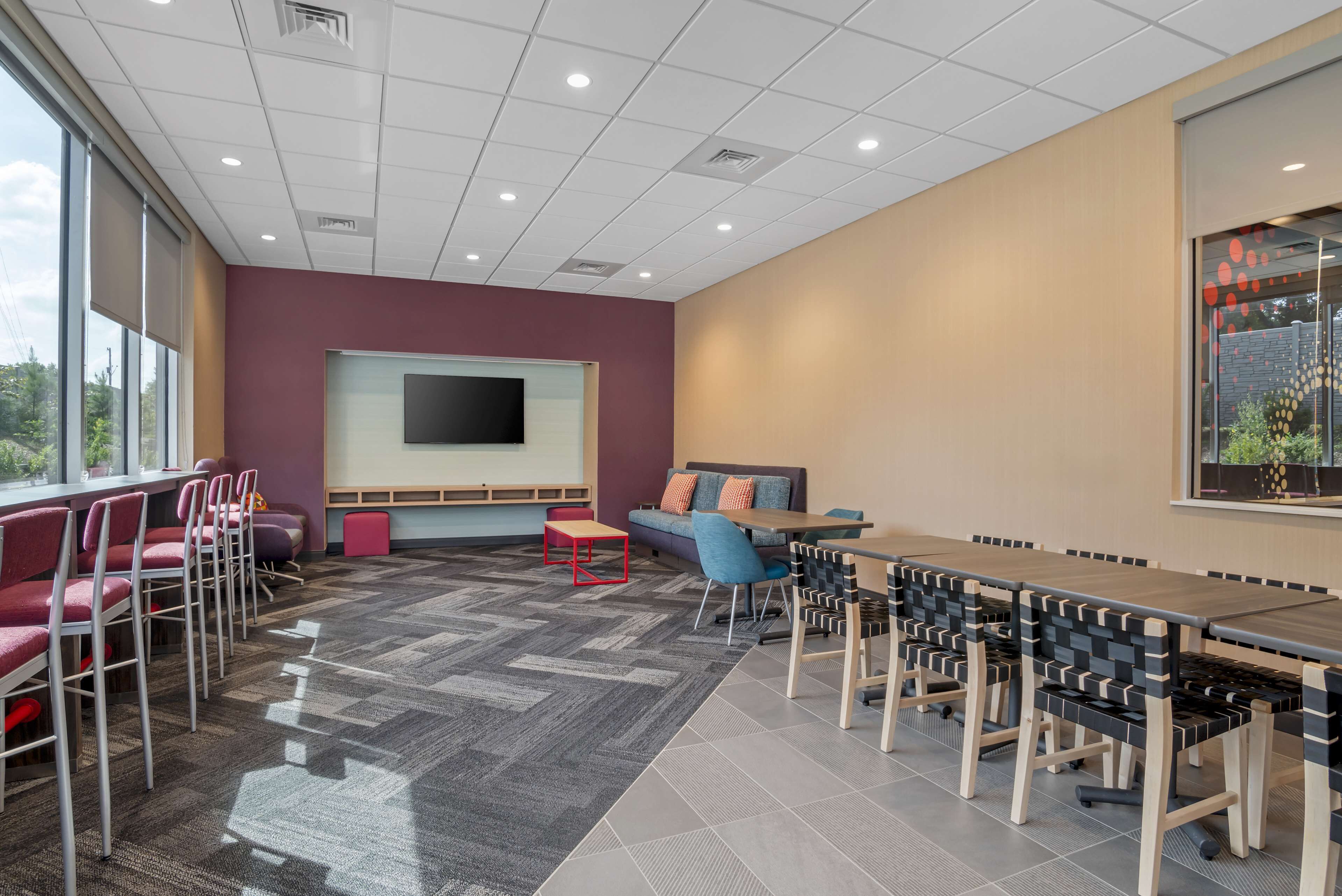 A modern meeting room with a large screen, comfortable seating, and a patterned carpet.