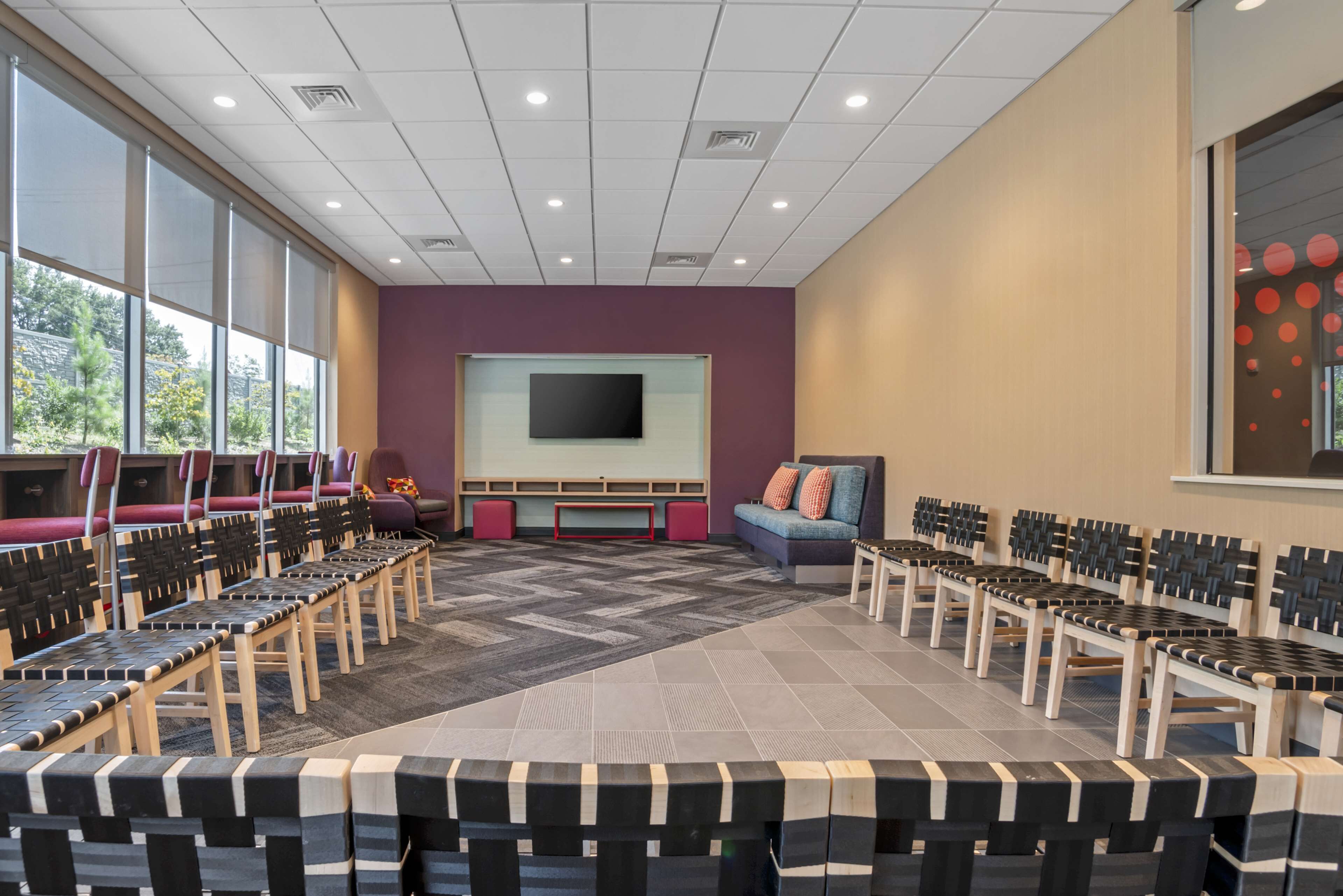 A conference room with rows of chairs, a large screen, and a sofa.