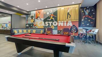 Een pooltafel in een moderne binnenruimte, met een kleurrijke muurschildering op de achtergrond.