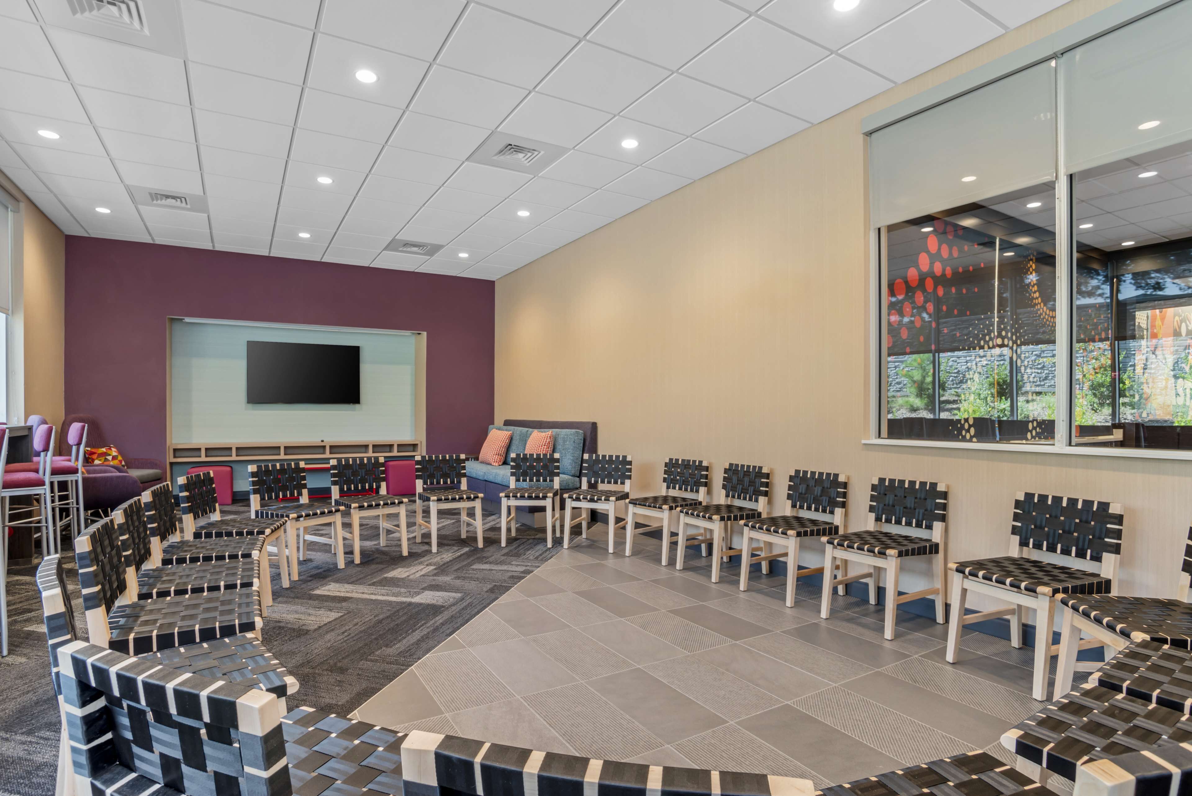 A conference room with a large screen, multiple chairs, and a carpeted floor.