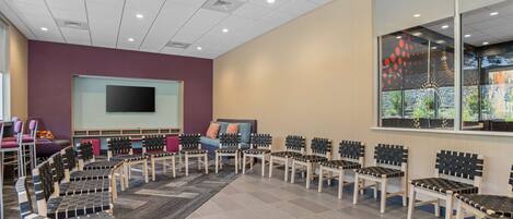 A conference room with a large screen, multiple chairs, and a carpeted floor.