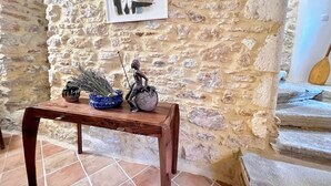 Een rustieke stenen muur met een lijst, een houten tafel met decoratieve objecten, en een trap met een houten leuning.
