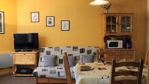 A living room with a sofa, television, wooden cabinet, and dining table. - 100m from ski slopes, 1st floor, balcony, tv, ski locker, 38m², Vars (Vars)