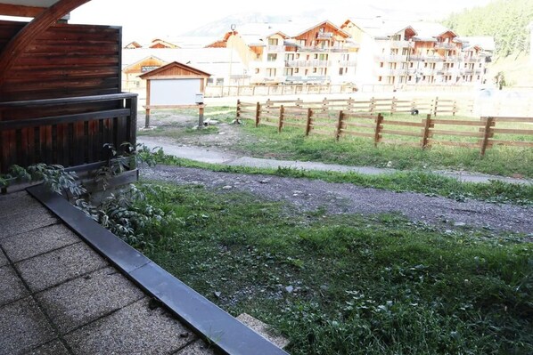A wooden balcony with a view of a mountain resort area, including a wooden fence and buildings in the background.