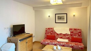 A small, cozy living room with a sofa, a television, a wooden cabinet, and a table with a tray. - Floor -1, view ski slopes, swimming pool, sauna, balcony, tv, ski locker, 29m², Les Orres (Les Orres)