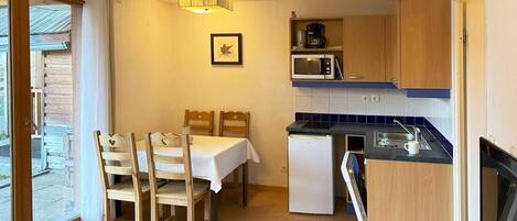 A compact kitchen with a dining area, a microwave, a coffee maker, and a refrigerator.