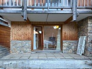 A wooden exterior with stone accents, a glass door entrance, and a metal gate.