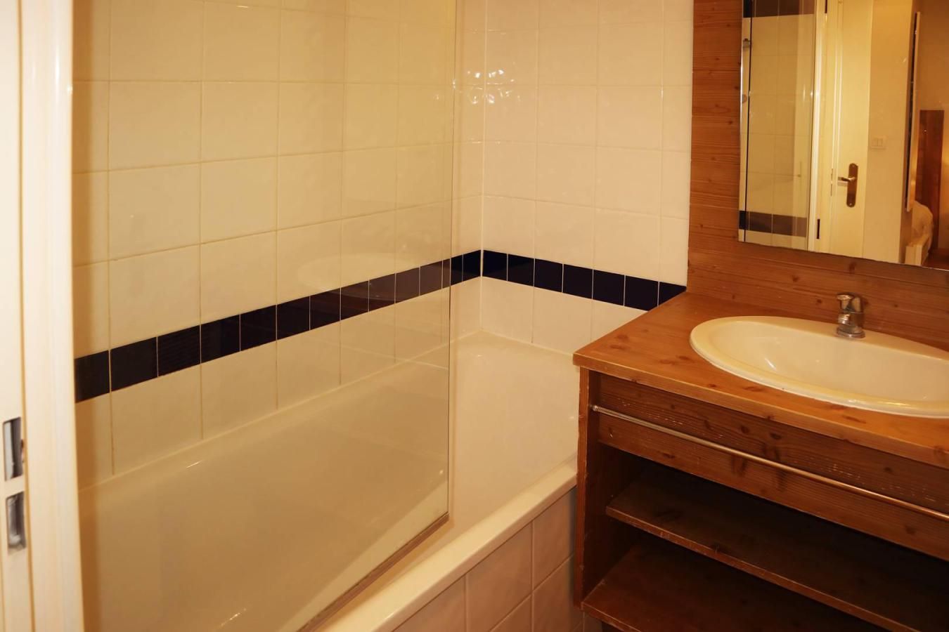 A bathroom with a bathtub, a wooden vanity with a sink, and a mirror.