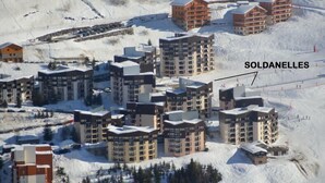 Une station de ski enneigée, avec plusieurs immeubles de grande hauteur portant l’inscription « SOLDANELLES ».