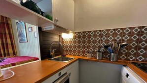 Une cuisine de taille réduite, dotée d’un plan de travail en bois, d’un évier, d’une cuisinière et d’un lave-vaisselle.