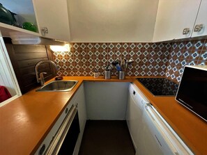 Compact kitchen with dishwasher, stainless steel sink, and small oven.