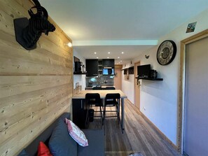 A compact living space with a kitchenette, a dining area, and a seating area with a sofa and a pillow. - 150m from shops, 3rd floor, view mountain, balcony, tv, ski locker, 27m², Les Menuires (Les Menuires)