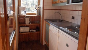 Una cocina compacta con lavavajillas integrado, microondas y fregadero.