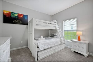 A bunk bed room with a Star Wars poster, a window with blinds, and a bedside table with a lamp. - Make your own Escape to Disney in this fantastic pool townhouse! (Davenport)