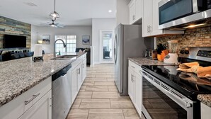 A modern kitchen with granite countertops, stainless steel appliances, and a central island. - Make your own Escape to Disney in this fantastic pool townhouse! (Davenport)