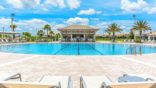 A swimming pool with lounge chairs and a covered seating area. - Make your own Escape to Disney in this fantastic pool townhouse! (Davenport)