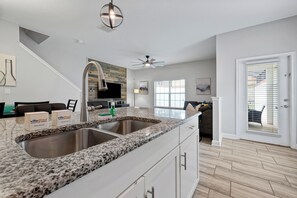 A modern kitchen with granite countertops, stainless steel appliances, and a farmhouse-style backsplash.
