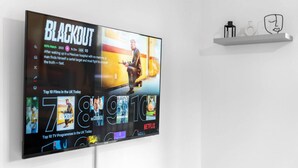 Un televisore montato a parete mostra un poster del film "Blackout" e un elenco dei migliori film e programmi TV nel Regno Unito.