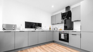 Una cucina moderna con mobili grigi, pavimento in legno, un forno a microonde, un lavello e un piano cottura.