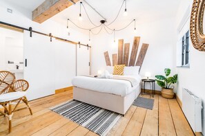 Una camera da letto moderna con un letto, pavimento in legno e un lampadario.