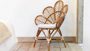 A wicker chair with a white cushion in a room with wooden flooring and white walls. - Newtown Lofts - Luxe Apartment - Parking (Birmingham)