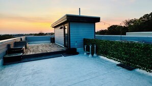 A modern building with a flat roof, a small entrance, and a wooden deck. - Stunning Private Rooftop Penthouse in DC! Modern Luxury with Breathtaking Views! (Washington)