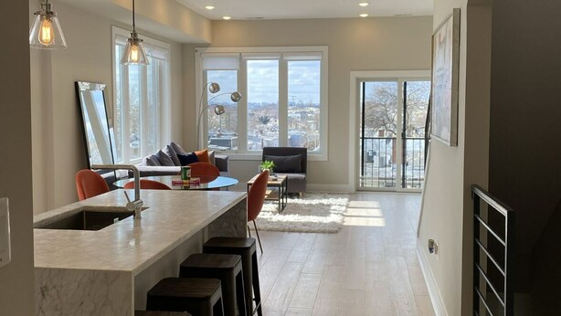 A modern kitchen with a marble island, bar stools, and pendant lighting. - Stunning Private Rooftop Penthouse in DC! Modern Luxury with Breathtaking Views! (Washington)