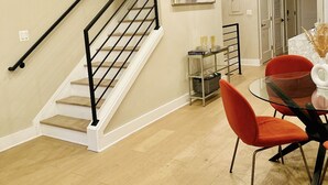A modern interior with a staircase, a dining area with red chairs, and a glass table. - Stunning Private Rooftop Penthouse in DC! Modern Luxury with Breathtaking Views! (Washington)