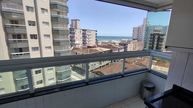 Un balcon offrant une vue sur un paysage urbain côtier, avec de nombreux bâtiments et un ciel dégag é.