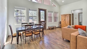 A spacious living area with a dining table and chairs, a sofa, and a wooden cabinet. - Pet-Friendly Show Low Cabin: Near Hiking! (Show Low)