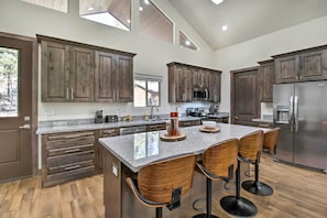 Enjoy cooking in this kitchen with a spacious island and bar stools, offering a functional workspace with a view of the surrounding landscape.