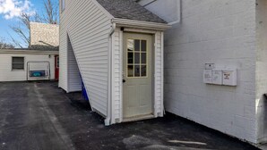 A white building with a small door and a window, a concrete ground, and a blue door frame. - Spacious Unit Sleeps 9 + Game Room! 15 Mins from New Bills Stadium (West Seneca)