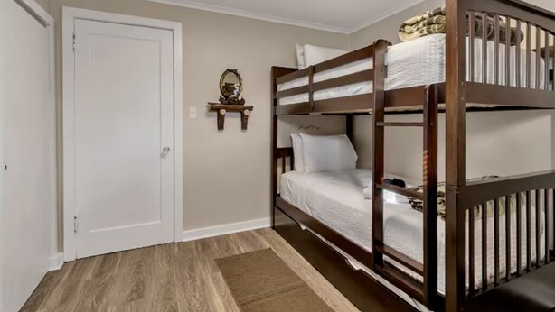 A room with a bunk bed, a white door, a small table with a mirror, and a brown rug. - Spacious Unit Sleeps 9 + Game Room! 15 Mins from New Bills Stadium (West Seneca)