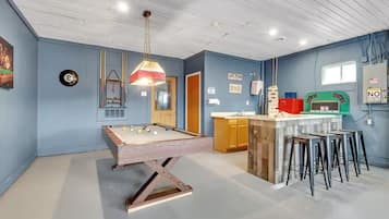 Une pièce comprenant une table de billard, un coin bar et un comptoir de cuisine.
