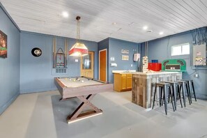 Um quarto com mesa de bilhar, bar e bancada de cozinha.