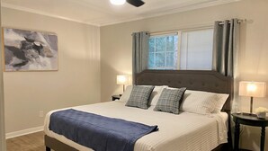 A bedroom with a large bed, two bedside tables, a ceiling fan, and a window with curtains. - The Quail's Nest! Convenient to downtown, quiet and fully remodeled! (Thomasville)